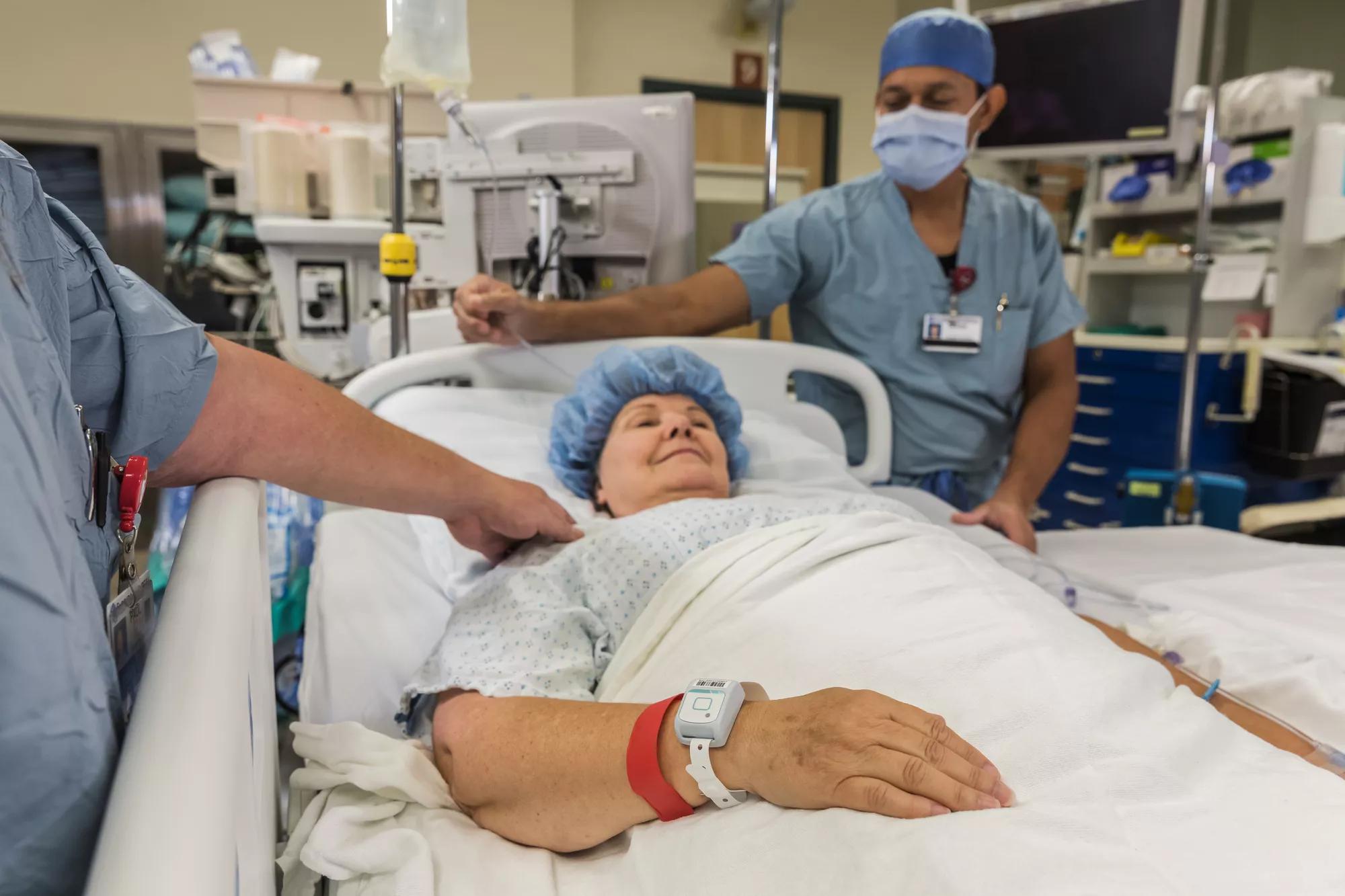 Patient in hospital bed, wearing the Patient flow tag while being cared for. Securitas Healthcare. 