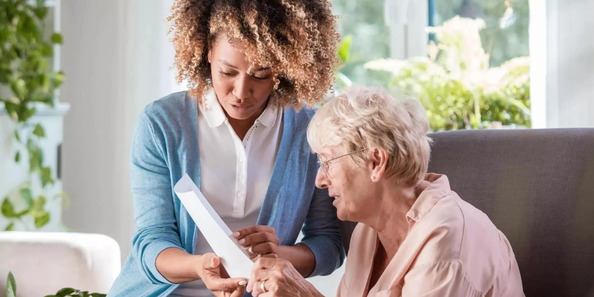 Senior Living caregiver helping resident to read
