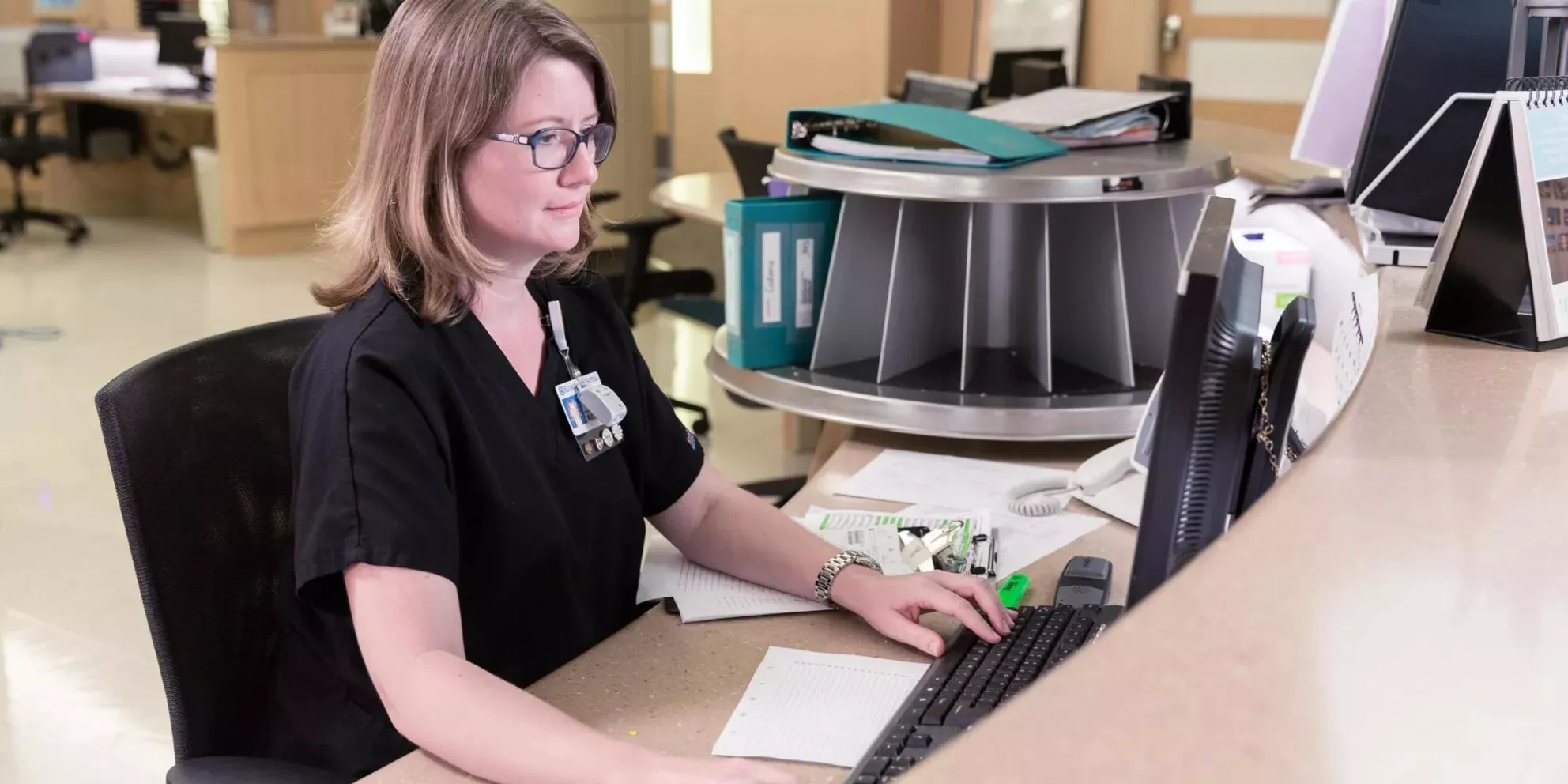 Caregiver on computer behind the nursing station