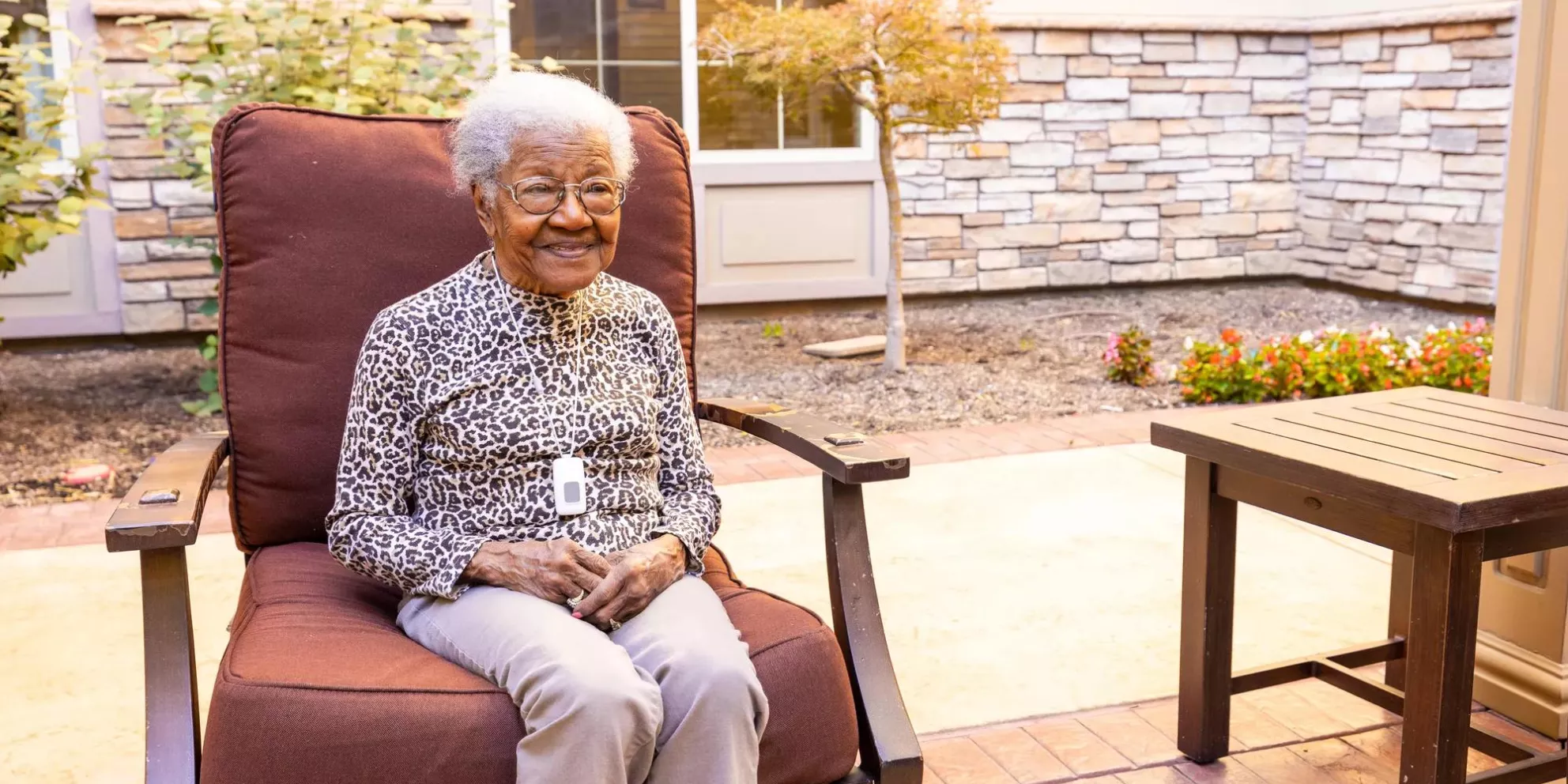 Senior living community resident seated outside, wearing Arial P10 e-call pendant. Securitas Healthcare.