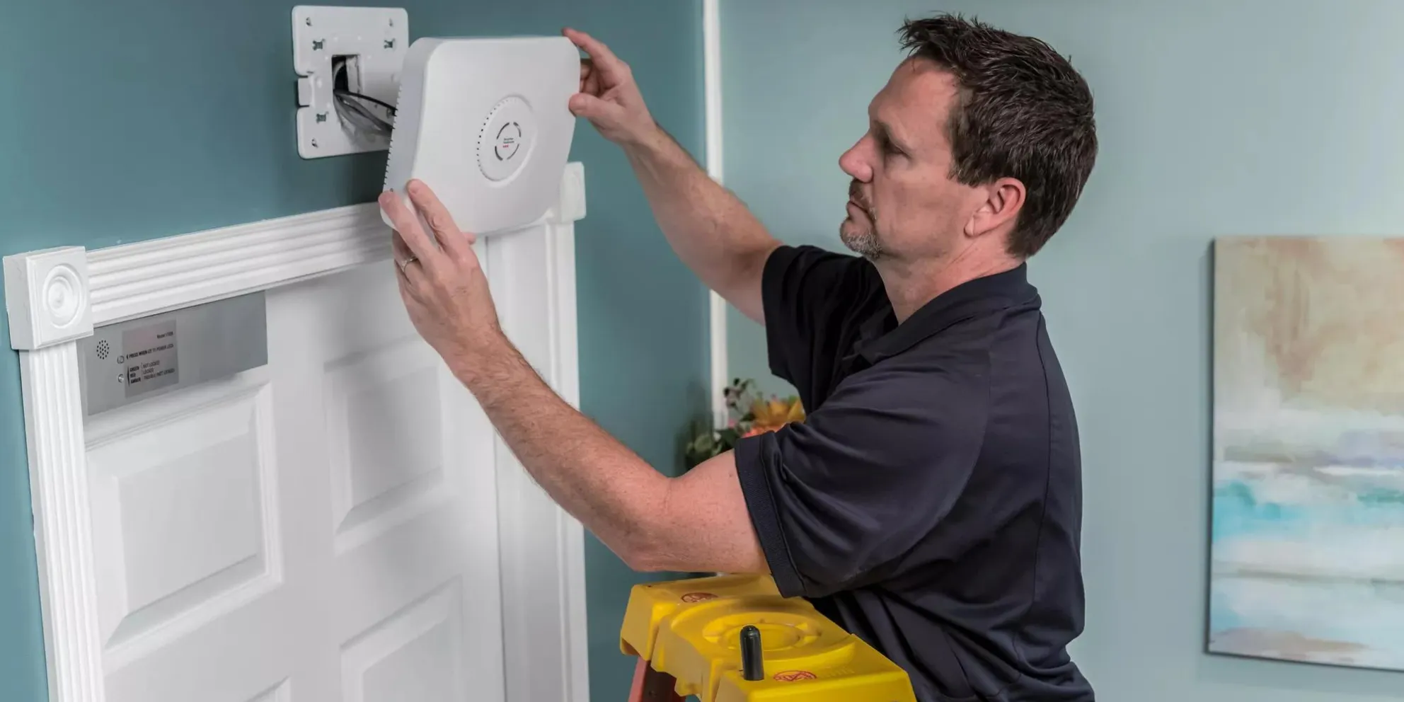 Securitas Healthcare technician installing a WanderGuard BLUE door controller in a senior living community. 