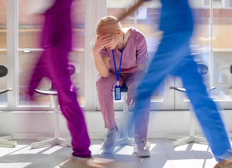 Workplace violence in hospital obstetrics. Distressed nurse taking break in a busy corridor.