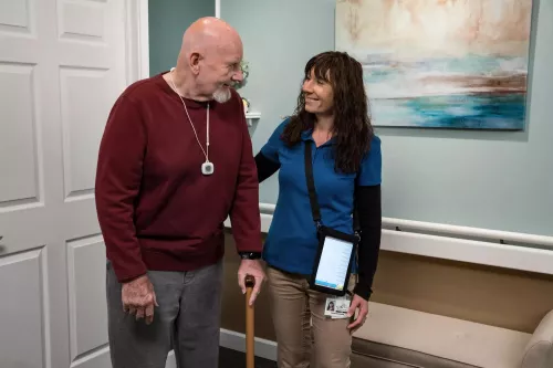 WanderGuard BLUE and Arial nurse call pendant on a senior living resident with caregiver assisting. Securitas Healthcare. 