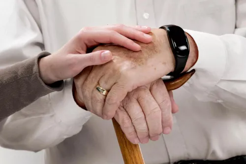 Senior living caregiver holding hand of community resident