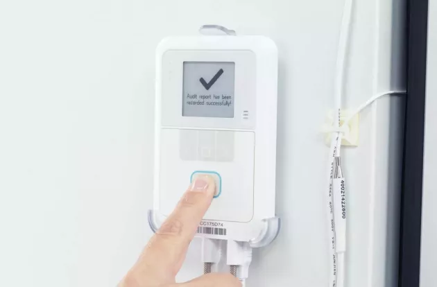 Caregiver pressing the button on the Securitas Healthcare T15e Temperature Monitoring sensor.