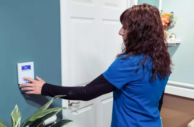Caregiver inputting code on the wall-mounted WanderGuard BLUE keypad, designed for use with Securitas Healthcare's wander management solution