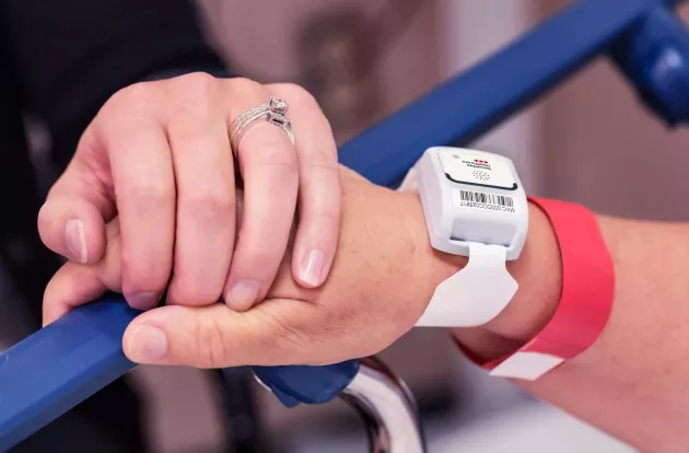 Patient protection T2 tag on a patient wrist, holding hands. Securitas Healthcare.