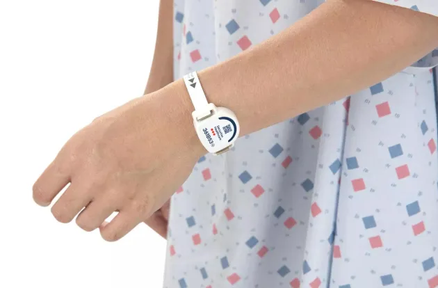 Patient in a hospital gown wearing the T8p Patient Protection band on their wrist. Securitas Healthcare.