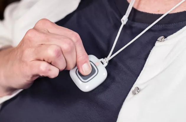 Securitas Healthcare, Arial wireless pendant being pressed. A nurse call solution for senior living facilities.