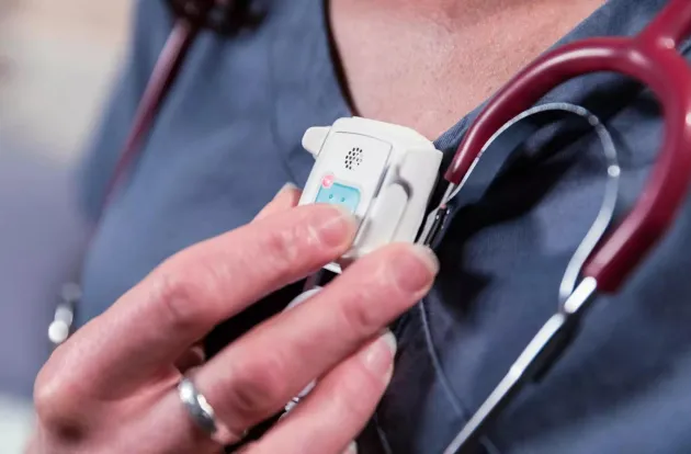 Caregiver pressing the alert button on the Securitas Healthcare T14 Staff Protection badge.