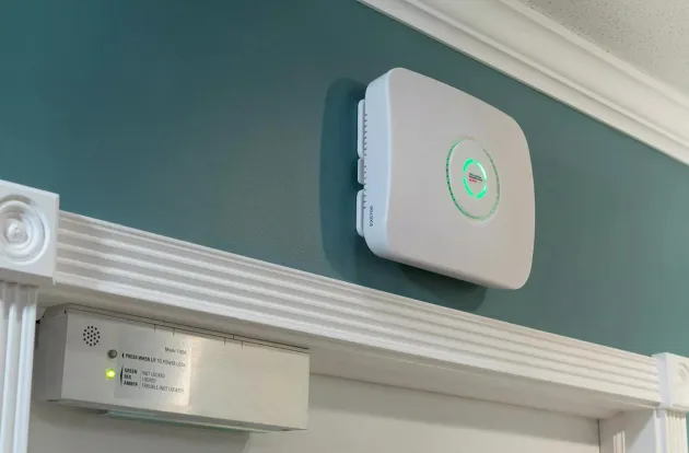 WanderGuard BLUE EX5700 Door Controller attached above door way, lit up with an alert for a wandering resident