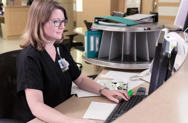 Caregiver on computer behind the nursing station