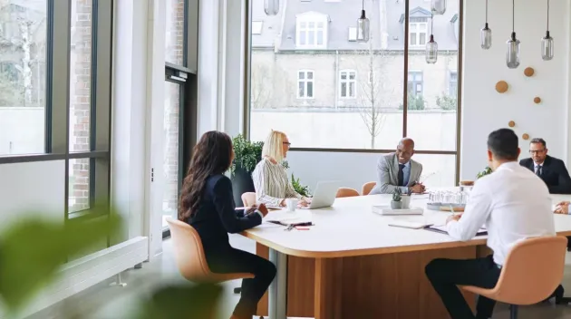 Smiling group of diverse businesspeople sitting around a boardroom table in an office during a meeting