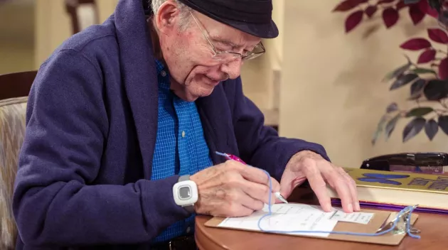 Resident filling out form while wearing Arial wrist bracelet