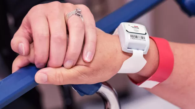 Patient protection T2 tag on a patient wrist, holding hands. Securitas Healthcare.