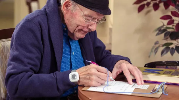 Resident filling out form while wearing Arial wrist bracelet
