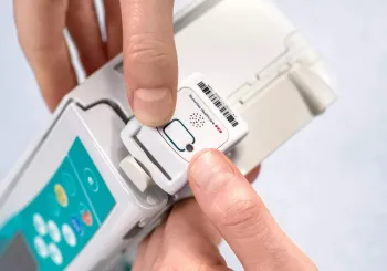 Engineer mounting Securitas Healthcare asset management tag to infusion pump