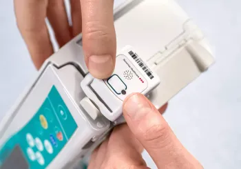 Engineer mounting Securitas Healthcare asset management tag to infusion pump