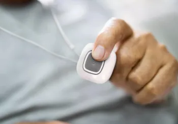Senior man pressing Securitas Healthcare Arial emergency call pendant to call for help