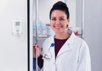 Pharmacist stands by refrigerator with Securitas Healthcare T15e environmental monitoring tag