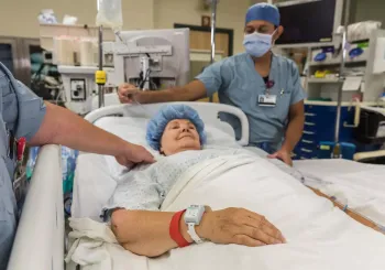 Patient in hospital bed, wearing the Patient flow tag while being cared for. Securitas Healthcare. 