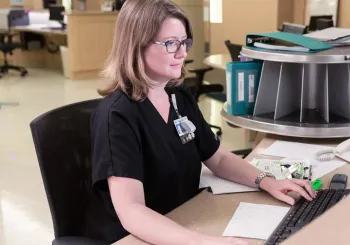 Caregiver on computer behind the nursing station