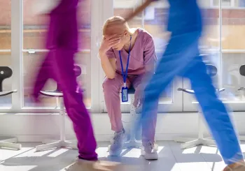 Workplace violence in hospital obstetrics. Distressed nurse taking break in a busy corridor.