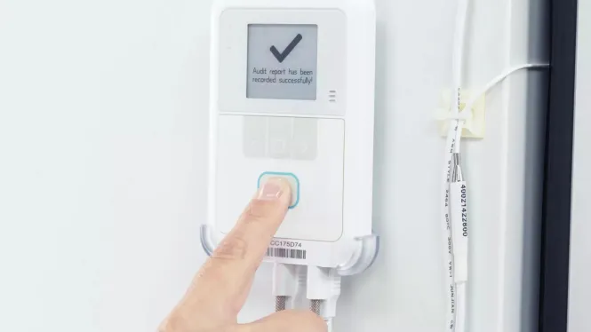 Caregiver pressing the button on the Securitas Healthcare T15e Temperature Monitoring sensor.
