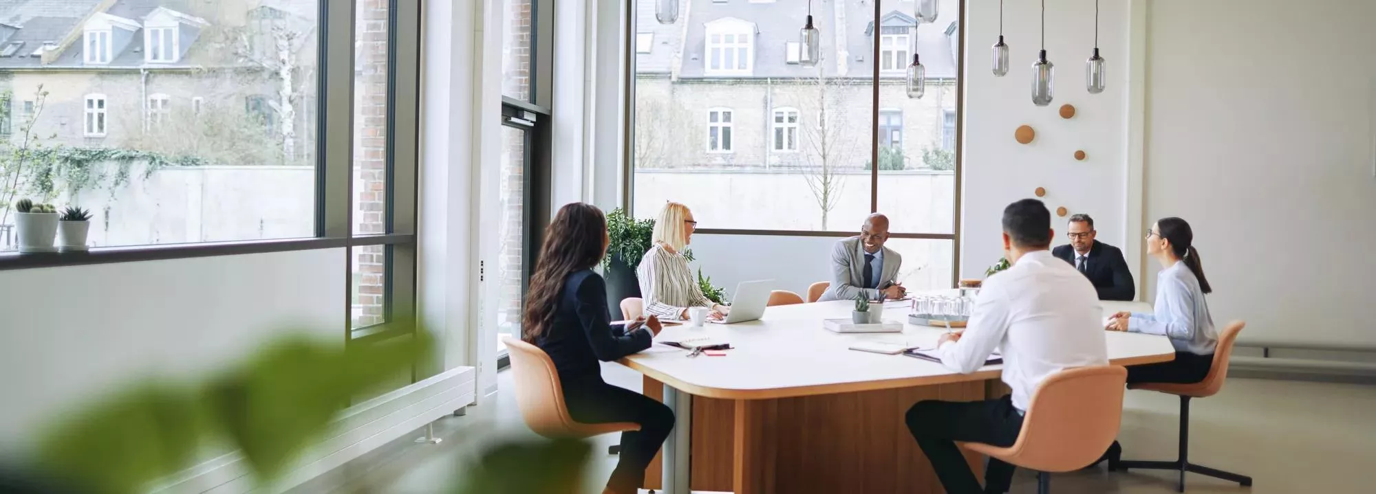 Smiling group of diverse businesspeople sitting around a boardroom table in an office during a meeting