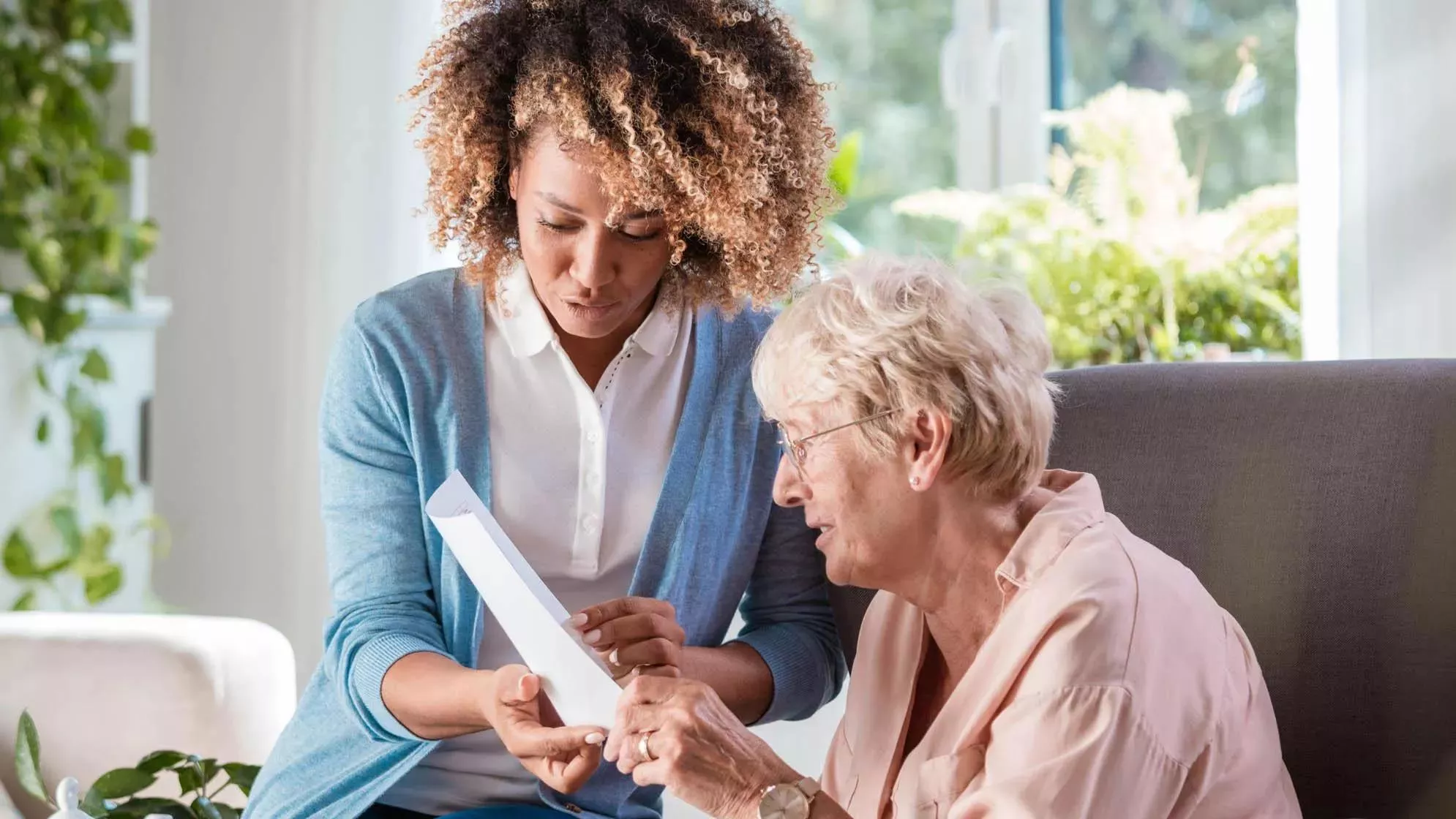 Senior Living caregiver helping resident to read