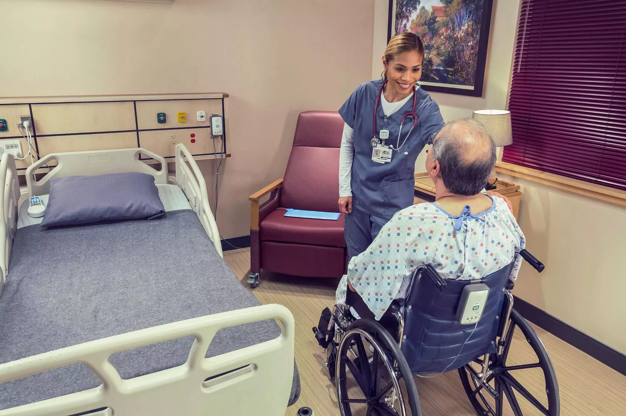 Nurse and patient in wheelchair with Fall Management M210 with hospital bed near by Securitas Healthcare.