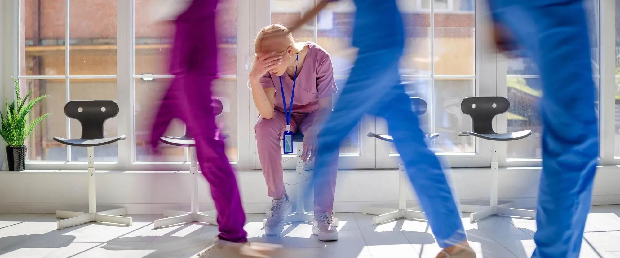 Workplace violence in hospital obstetrics. Distressed nurse taking break in a busy corridor.