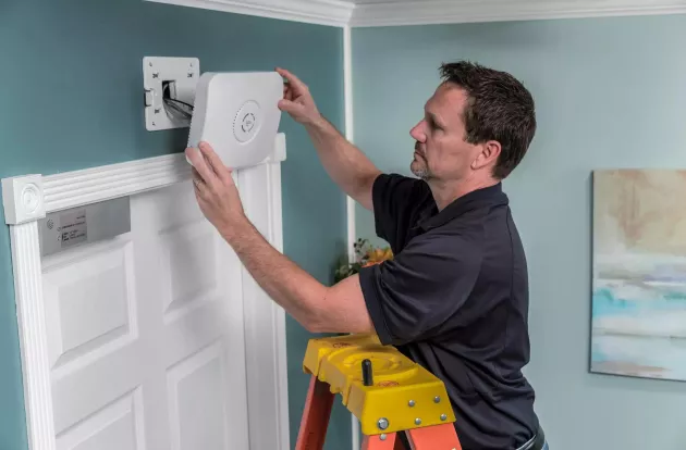 Securitas Healthcare technician installing a WanderGuard BLUE door controller in a senior living community. 