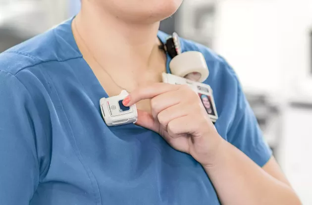 Nurse pressing button of Securitas Healthcare staff protection tag to call for assistance