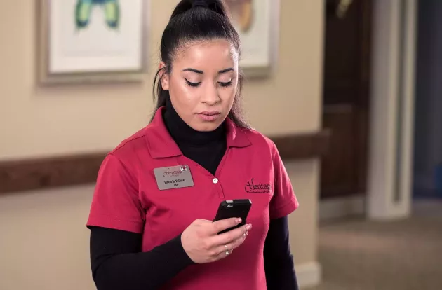Senior Living caregiver checking the Securitas Healthcare Arial mobile application on her smartphone