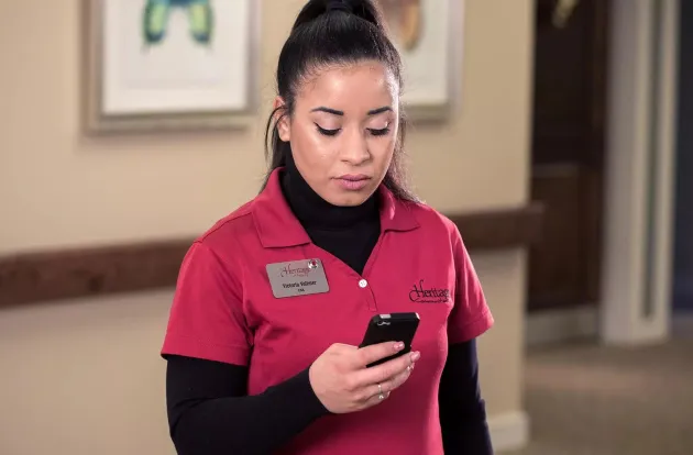 Senior Living caregiver checking the Securitas Healthcare Arial mobile application on her smartphone