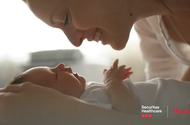 New mother cradling and smiling down at newborn baby