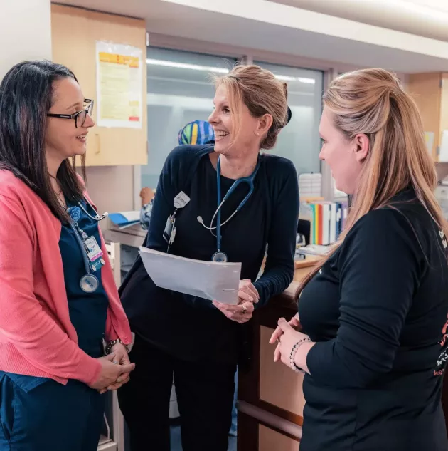 A group of 3 nurses gathered and talking .