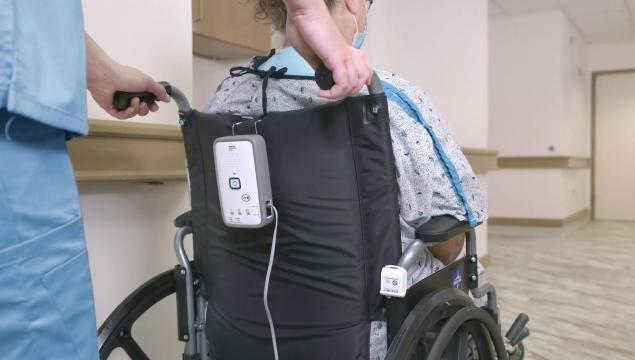 Nurse pushing patient in wheelchair with Securitas Healthcare M210 fall monitor