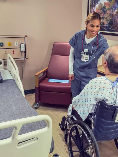 Nurse and patient in wheelchair with Fall Management M210 with hospital bed near by Securitas Healthcare.