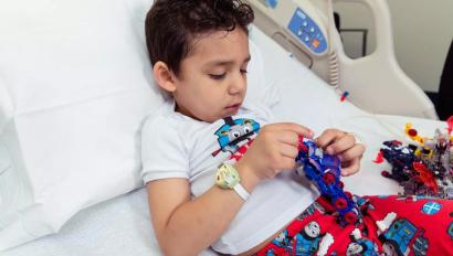 Young boy laying in hospital bed wearing the Hugs Infant Protection solution band around his wrist
