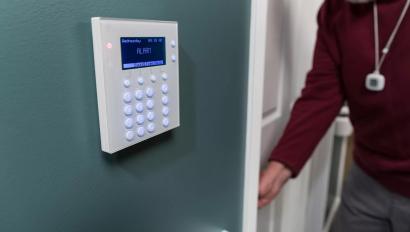 Resident wearing a Securitas Healthcare Arial pendant, entering room near an access point for WanderGaurd Blue. 