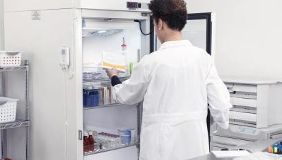 A pharmacist placing temperature-sensitive materials into a medication fridge while the T15e digital data logger monitors temperature.