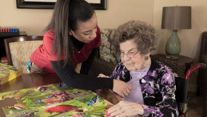 Senior Living community caregiver visits with resident, who uses an Arial e-call pendant by Securitas Healthcare