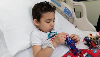 Pediatric patient boy laying in hospital bed wearing the Hugs Infant Protection solution band around his wrist. Securitas Healthcare.