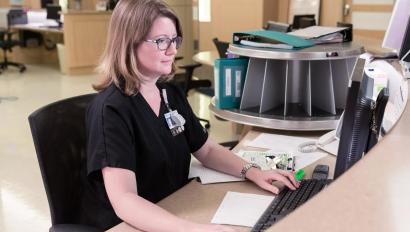 Caregiver on computer behind the nursing station