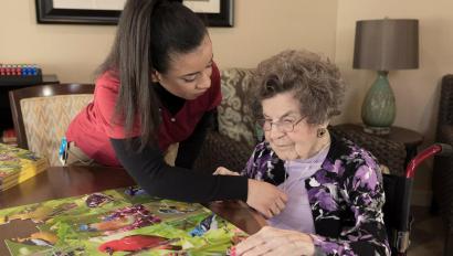 Senior Living community caregiver visits with resident, who uses an Arial e-call pendant by Securitas Healthcare