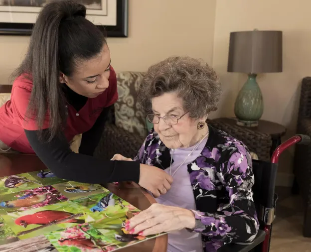 Senior Living community caregiver visits with resident, who uses an Arial e-call pendant by Securitas Healthcare