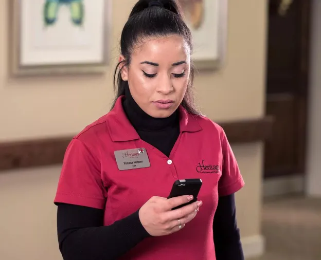 Senior Living caregiver checking the Securitas Healthcare Arial mobile application on her smartphone